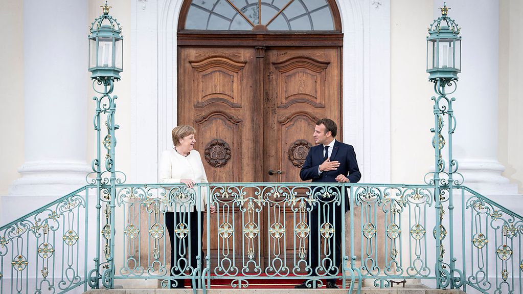 Federal Chancellor Merkel and President Macron in front of a door.