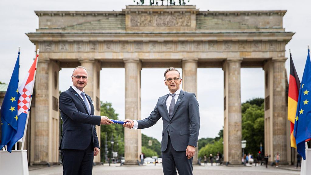 Außenminister Maas (links) bekommt den symbolischen Staffelstab am Brandenburger Tor von seinem kroatischen Amtskollegen Radmann überreicht.