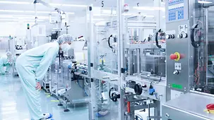 Ein Labormitarbeiter kontrolliert eine Maschine zur Produktion von Arzneimitteln. 