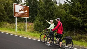 Zwei Radfahrer vor einem Hinweisschild