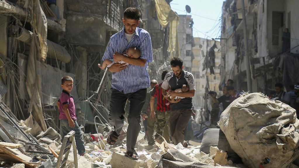 In Syria, a man rescues a small child from a pile of rubble.