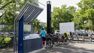 Eine Fahrradfahrerin stellt ihr Rad an einer der Radstätten am Radweg Deutsche Einheit ab.