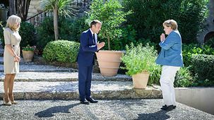 Chancellor Angela Merkel and French President Emmanuel Macron greet one another.