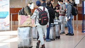 Reisende stehen im Terminal am Flughafen Hamburg Schlange an einem Check-In-Schalter. 