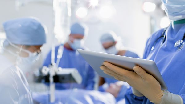 Telemedizin - Ärzte im OP mit Tablett in der Hand