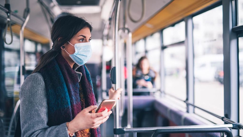 Coronavirus: Eine Frau steht in einer Straßenbahn und trägt eine Maske.