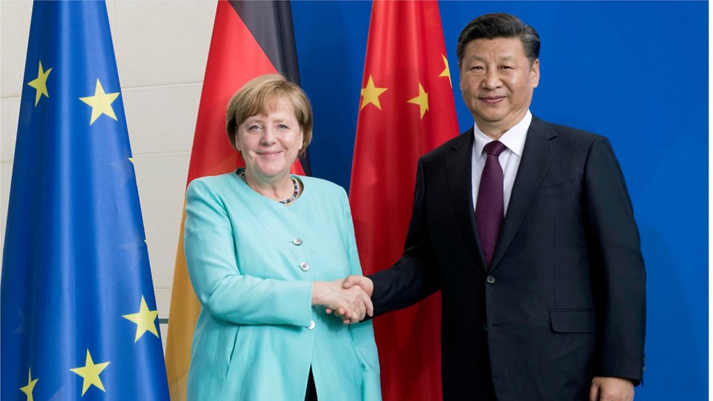 Bundeskanzlerin Angela Merkel schüttelt dem chinesischen Präsidenten Xi Jinping für ein Foto die Hand. Im Hintergrund sind die Flaggen der EU, Deutschlands und Chinas zu sehen. 