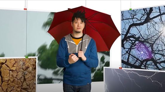 Foto zeigt den Sprecher des Videos mit aufgespanntem Regenschirm
