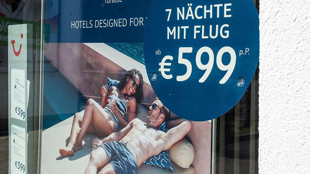 Plakat im Schaufenster eines Reisebüro wirbt für eine Pauschalreise.