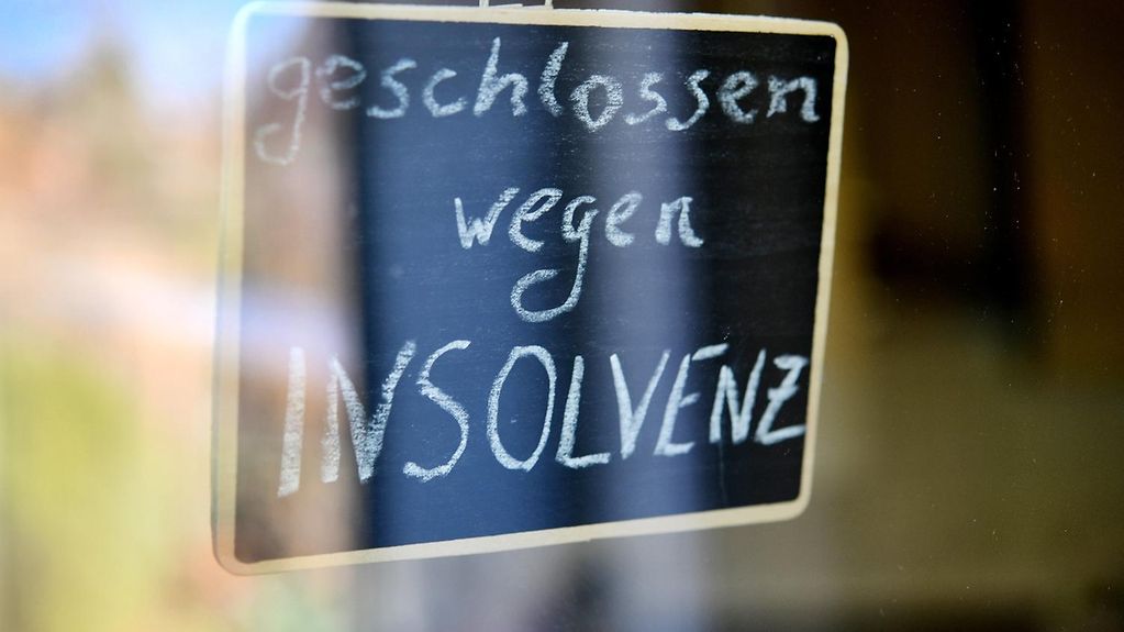 Das Bild zeigt ein Schild hinter einer Glastür, auf dem "Geschlossen wegen Insolvenz" steht.