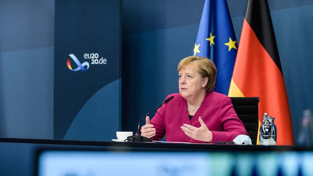 Chancellor Angela Merkel at a desk in the Federal Chancellery during a video conference of the Tripartite Social Summit