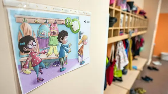 Ein Plakat in der Umkleide einer Kita macht Kinder auf spielerische Weise auf Abstände aufmerksam.