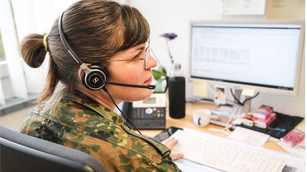 Eine Soldatin der Bundeswehr telefoniert in einem Gesundheitsamt mit einem Headset.