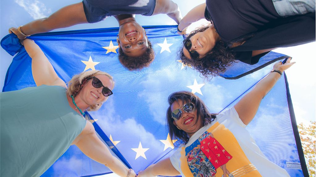Vier Frauen halten eine europäische Flagge in der Luft.