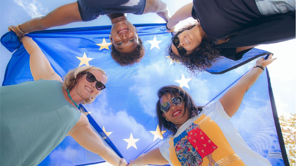 Quatre femmes tiennent un drapeau européen en l’air.