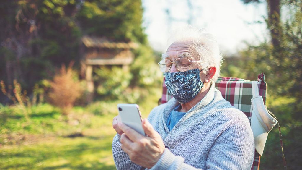 Ein Rentner liest Nachrichten auf seinem Handy 