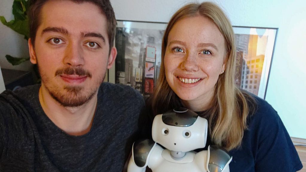 Ein junger Mann und eine junge Frau, die junge Frau hält einen Roboter im Arm