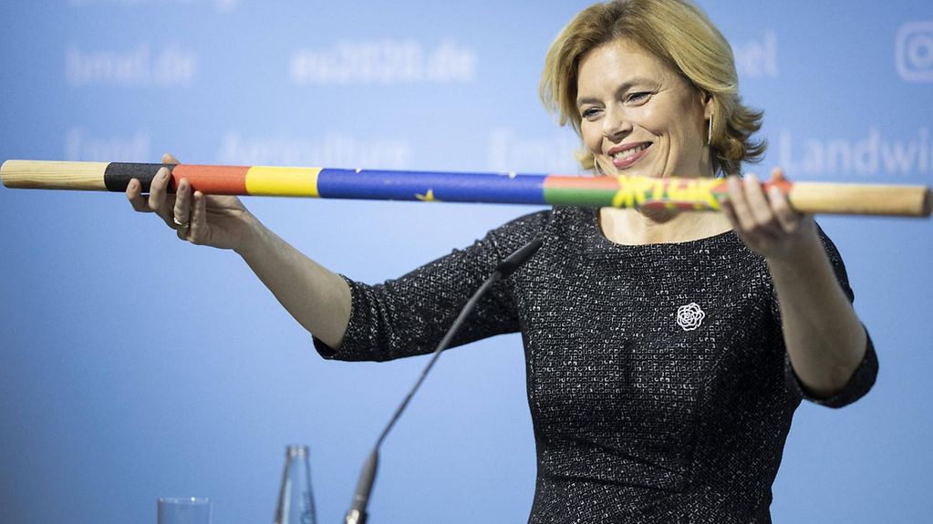 Das Bild zeigt Ministerin Klöckner, die einen symbolischen Staffelstab übergibt.
