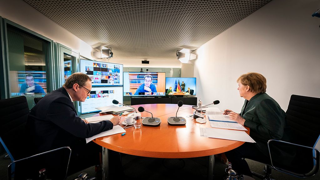 Kanzlerin Merkel und Berlins Regierender Bürgermeister Müller sitzen im Kanzleramt und nehmen an der Videokonferenz über die aktuellen Corona-Maßnahmen teil.
