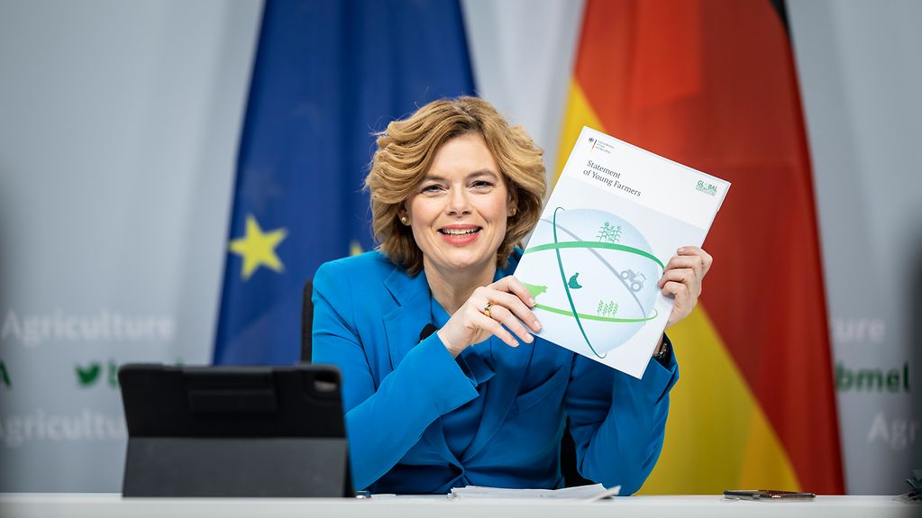 Bundeslandwirtschaftsministerin Julia Klöckner hält eine Broschüre hoch.
