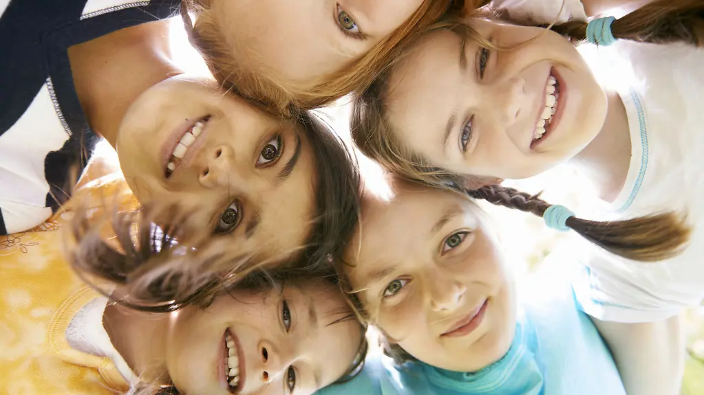 Fröhliche Kinder stecken die Köpfe zusammen und lachen gemeinsam.