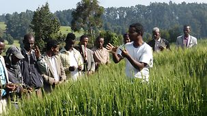 Ein Äthiopier spricht mit Männern in einem Feld.