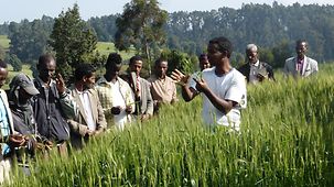An Ethiopian speaks to a group of men in a field.