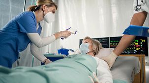 Krankenschwester mit Covid-19 infizierter Patient im Bett im Krankenhaus