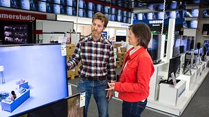 Verbraucher schauen sich in einem Elektromarkt ein TV-Gerät an