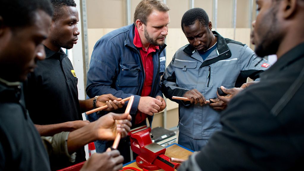 Junge Afrikaner mit Ausbilder in einer Lernwerkstatt.