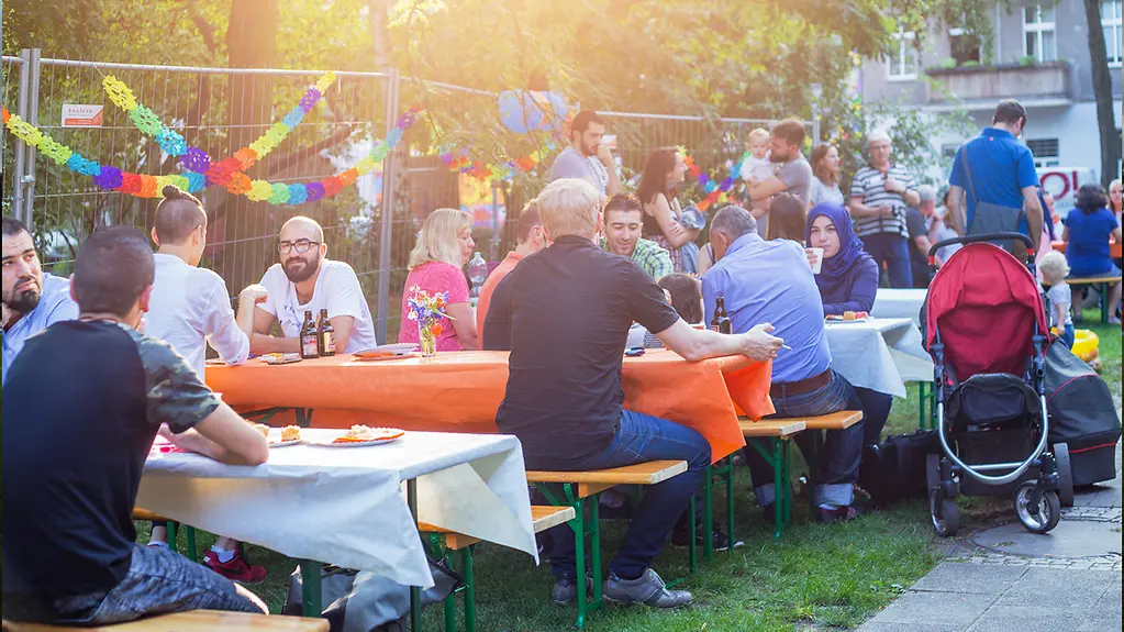 Menschen sitzen auf Bänken an Tischen