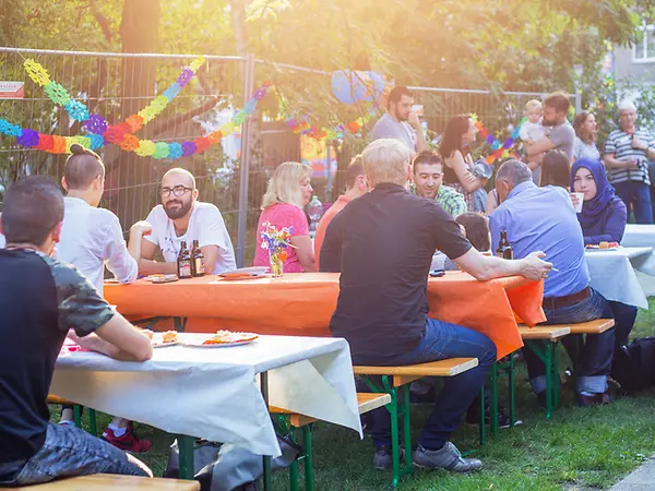 Menschen sitzen auf Bänken an Tischen