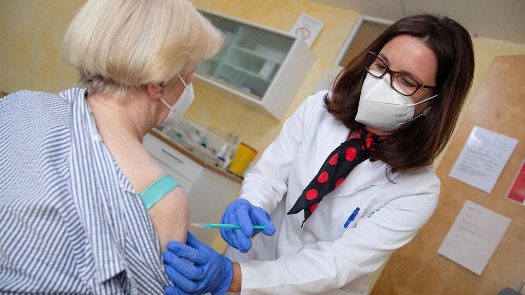 Eine Hausärztin spritzt einer Patientin Impfstoff gegen das Coronavirus in den Oberarm.