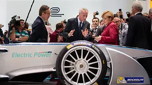 Chancellor Angela Merkel stands behind a electric racing car.