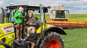 Foto zeigt einen Landwirt mit seinen Kindern auf einem Traktor. 