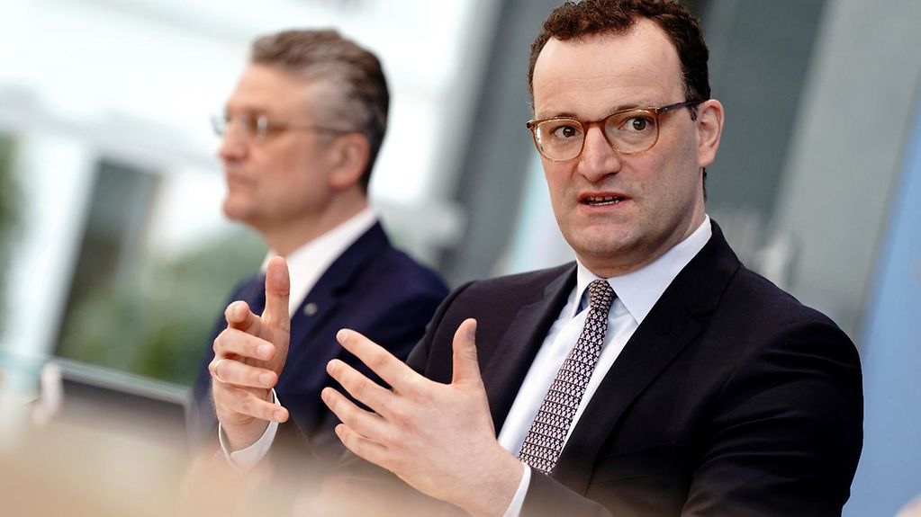 Das Bild zeigt Bundesgesundheitsminister Jens Spahn im Vordergrund und RKI-Präsident Lothar Wieler im Hintergrund. Beide sitzen auf dem Podium der Bundespressekonferenz.