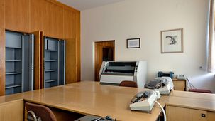 Büroraum mit holzvertäfelten Schränken, Tischen und Stühlen