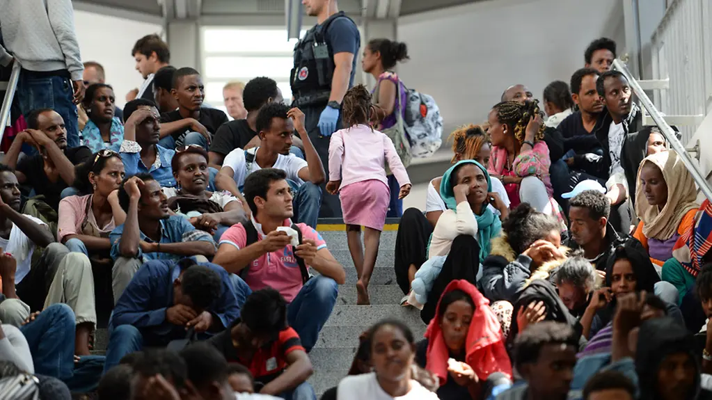 Refugees sitting on a stairway at the train station in Rosenheim