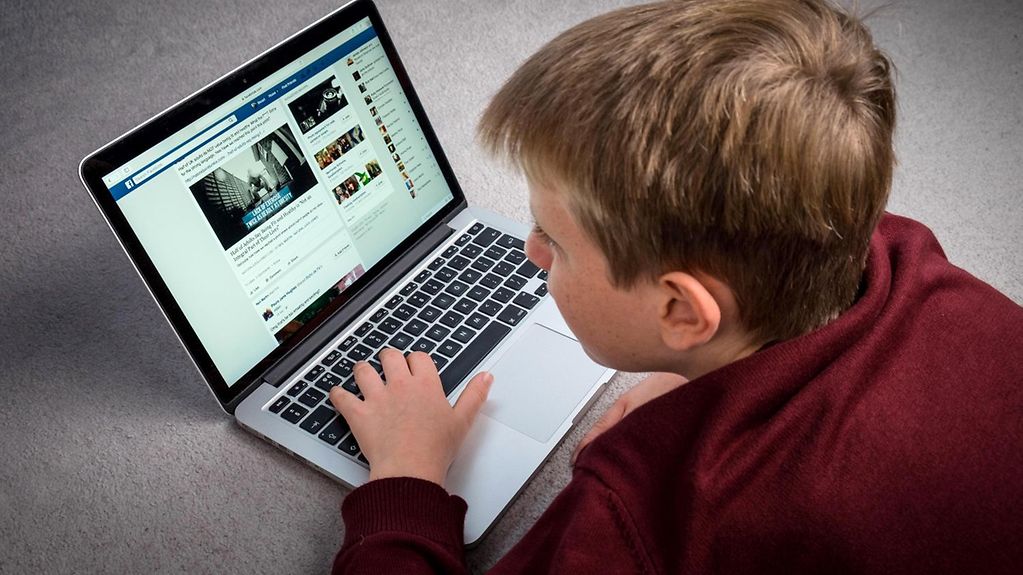 Das Bild zeigt ein Kind mit einem Laptop.