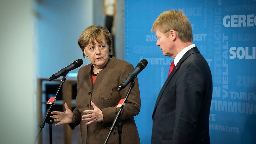 Bundeskanzlerin Angela Merkel sitzt bei der Bundesvorstandsklausur des Deutschen Gewerkschaftsbunds neben dem Vorsitzenden Reiner Hoffmann.