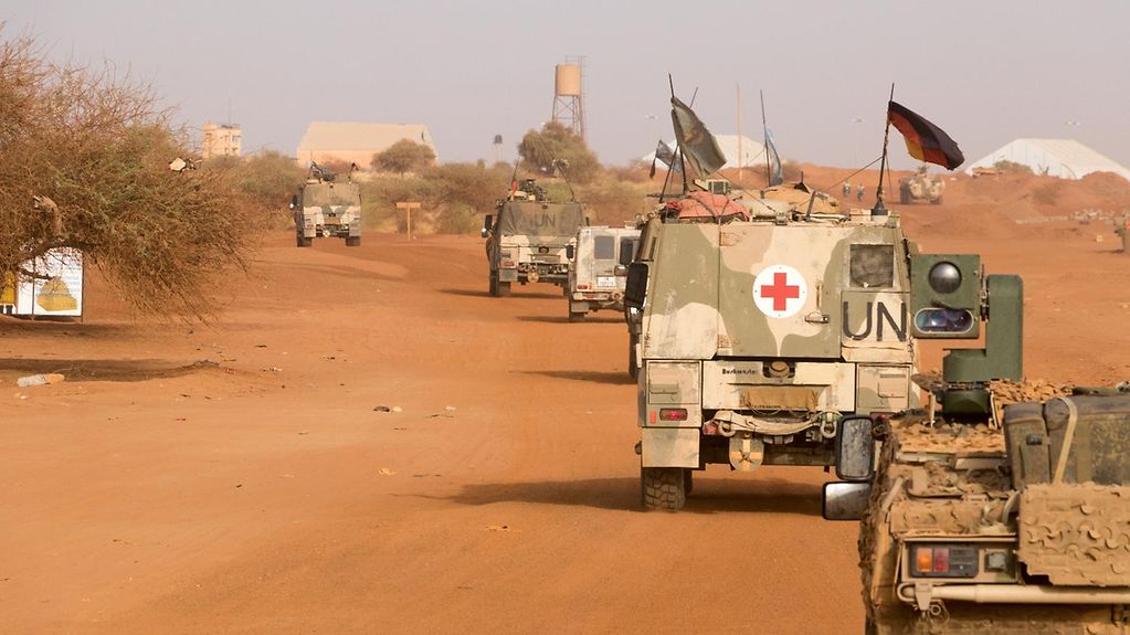Soldiers in armoured vehicles on patrol on a sandy road through Gao in Mali