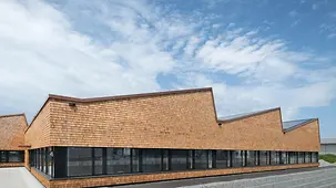 Eine Halle in Holzbauweise mit Produktions- und Büroarbeitsplätzen im Plusenergie-Standard.