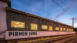 Sanierter ehemaliger Güterbahnhof-Schuppen mit einer Gebäudehülle aus Holztafelkonstruktion.
