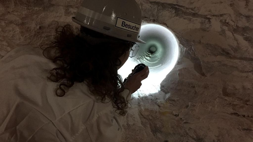 Forscherin blickt mit Taschenlampe in einen Kavernenhohlraum
