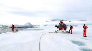 Forscher neben ihrem Hubschrauber im Eis von Grönland.