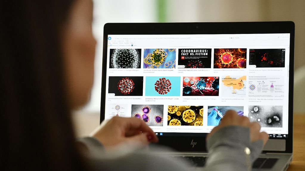 A woman at a laptop performing an image search on the coronavirus.