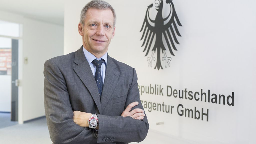 Thomas Weinberg vor eine Schild der Bundesrepublik Deutschland Finanzagentur GmbH