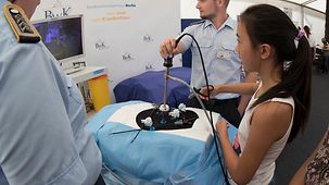 Eine Besucherin testet im Zelt des Bundeswehrkrankenhauses Berlin selbst eine OP-Technik.