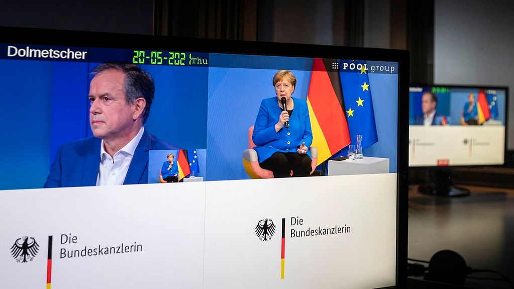 Kanzlerin Merkel und Andreas Cichowicz, Chefredakteur Norddeutscher Rundfunk, sind während ihrer Videoschalte auf zwei Bildschirmen zu sehen.