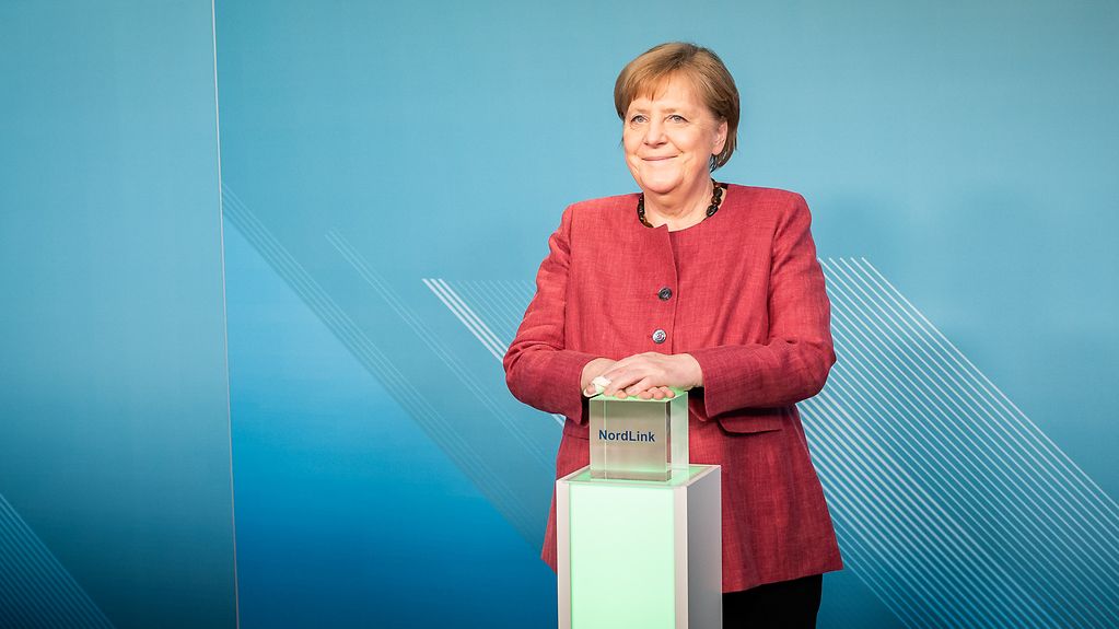 Kanzlerin Merkel drückt den Knopf für den Start der neuen Stromverbindung